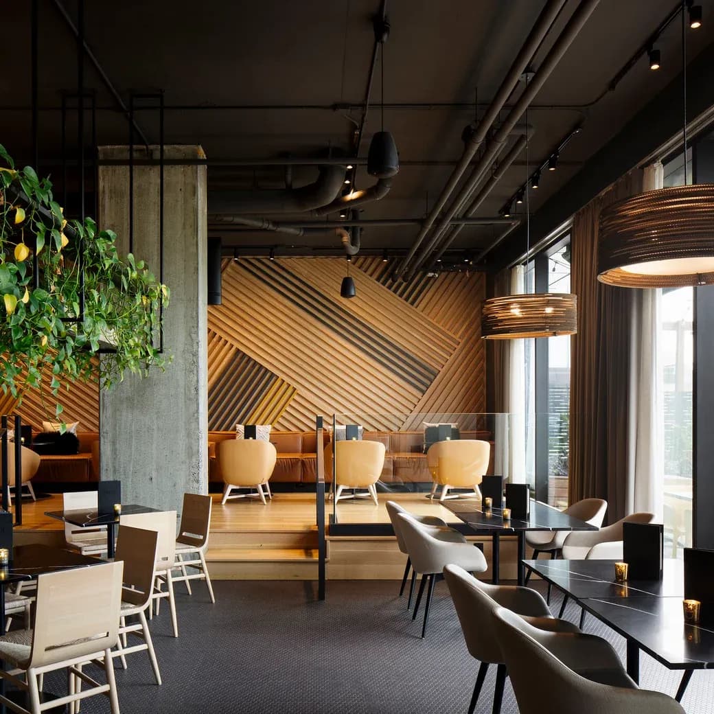 Restaurant with a raised seating area, a leather banquette against a slatted wood feature wall, drum pendant lights and black tables